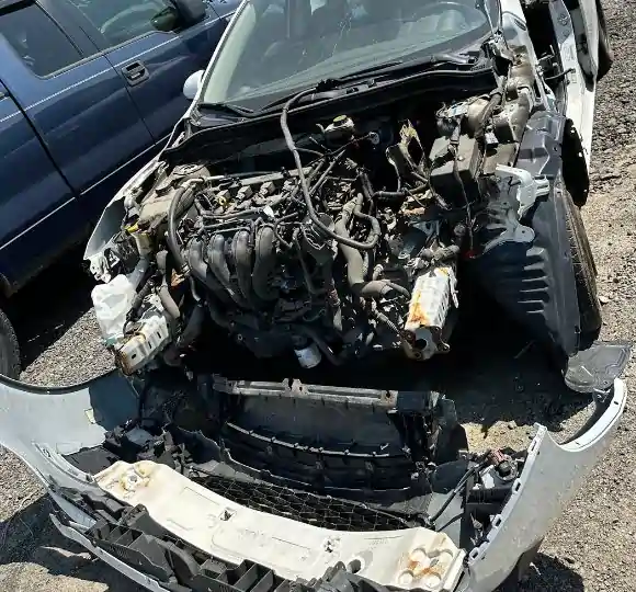 Heavily wrecked white junk car with destroyed engine bay at scrap yard for scrap car removal Toronto