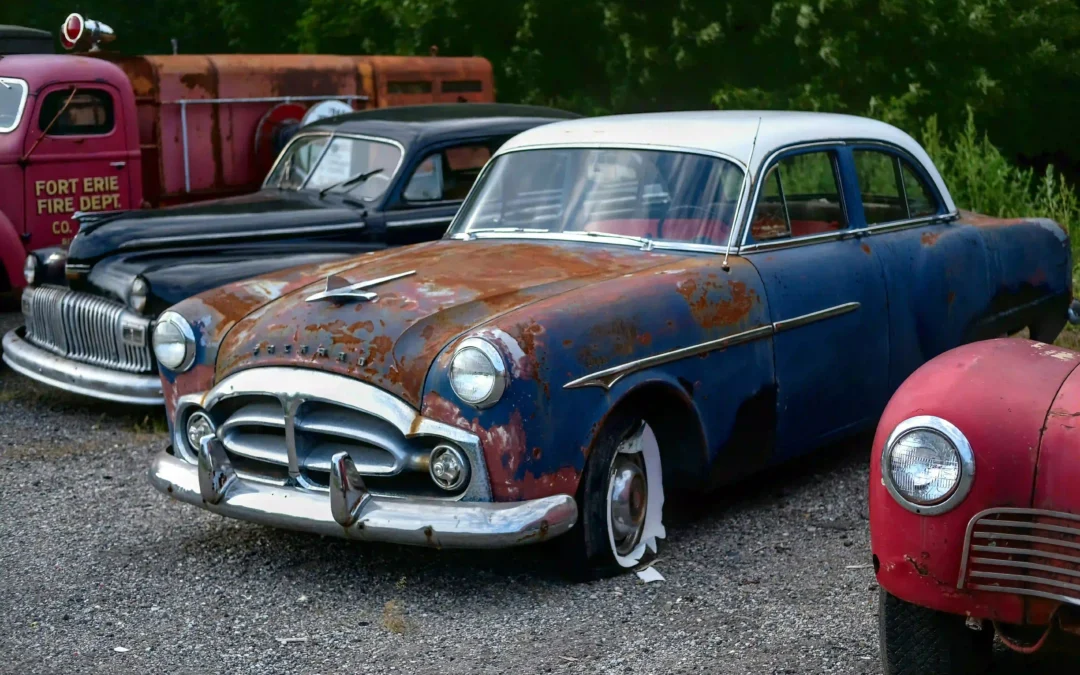 Multiple rusty abandoned vintage scrap cars parked on gravel lot ideal for scrap car removal services
