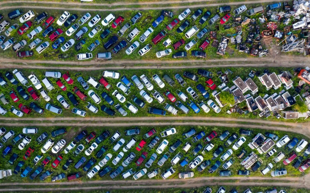 Aerial view of hundreds of junk and scrap cars lined up in rows at a large auto salvage yard.