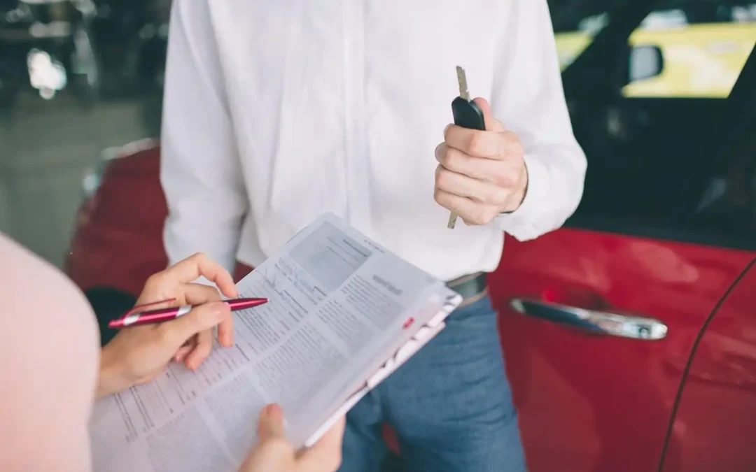 Signing vehicle ownership documents and handing over car keys during a car sale or scrap transfer.