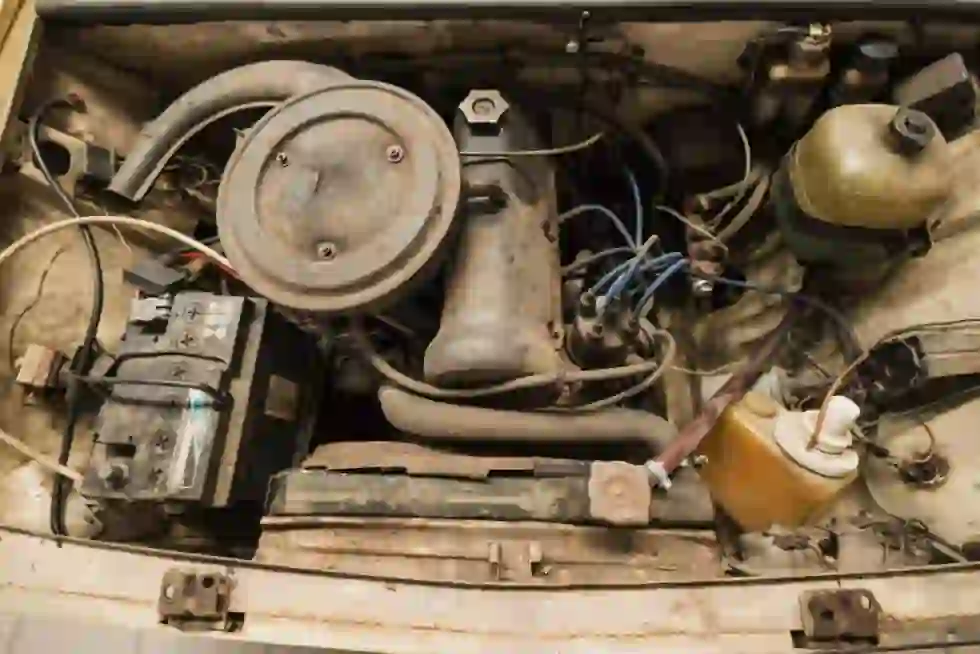 Rusty old car engine bay with a worn lead-acid battery