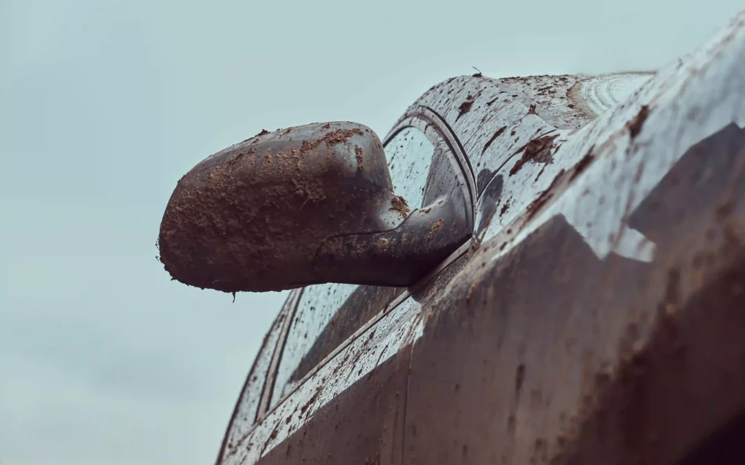 A heavily rusted, mud-caked car side mirror — a clear visual sign the vehicle is past its useful life