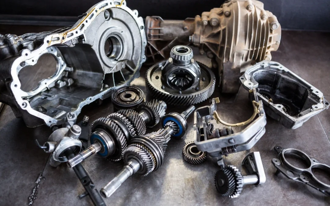 Disassembled transmission and differential parts - gears, shafts, casings, bearings - laid out on a workshop floor.